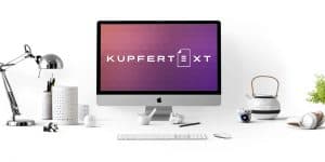 Kupfertext-Logo auf Mac-Bildschirm. Schreibtisch mit Lampe, Computer und div. Arbeitsutensilien